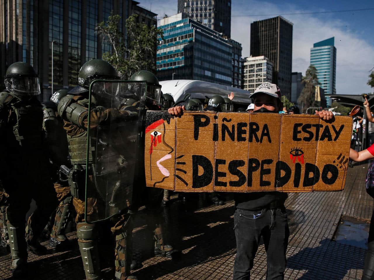 A demonstrator holds a sign reading 'Pinera you're fired' amid protests to call for step down of Chilean president (AFP)
